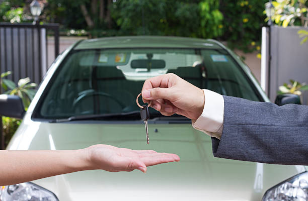 Consumidor recebe a chave do carro que comprou em frente ao carro adquirido