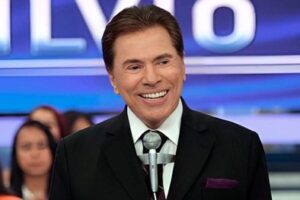 Silvio Santos, em meio corpo e muito sorridente em seu auditório